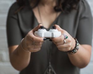 A person holding a white game controller with both hands