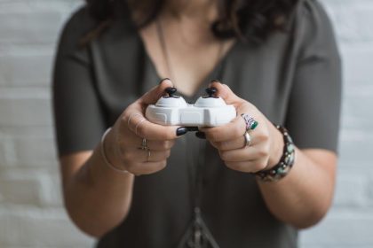 A person holding a white game controller with both hands