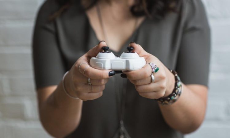 A person holding a white game controller with both hands