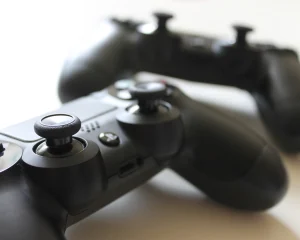 Two black game controllers resting on a white table