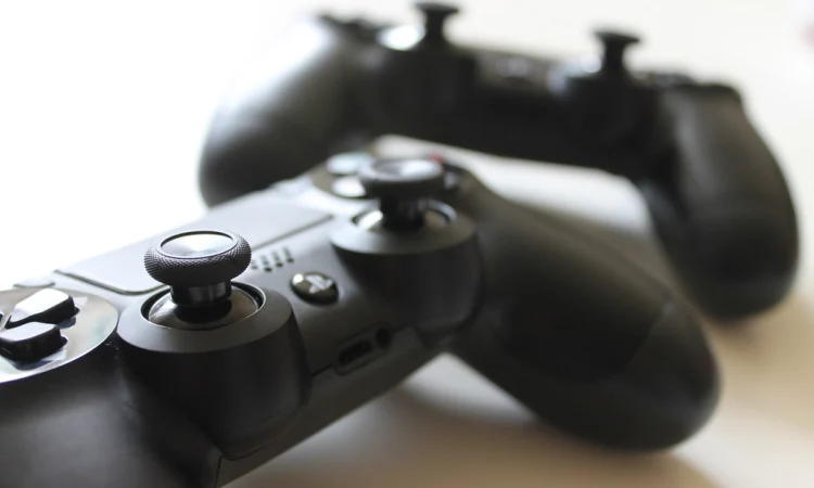 Two black game controllers resting on a white table